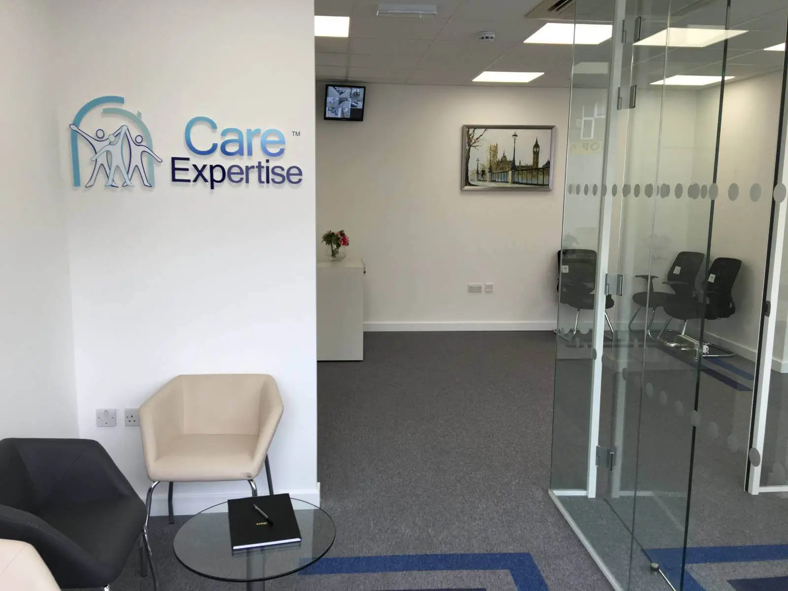 Care Expertise health care space with designer furniture, suspended grid ceiling, carpet tile flooring and glass partitions