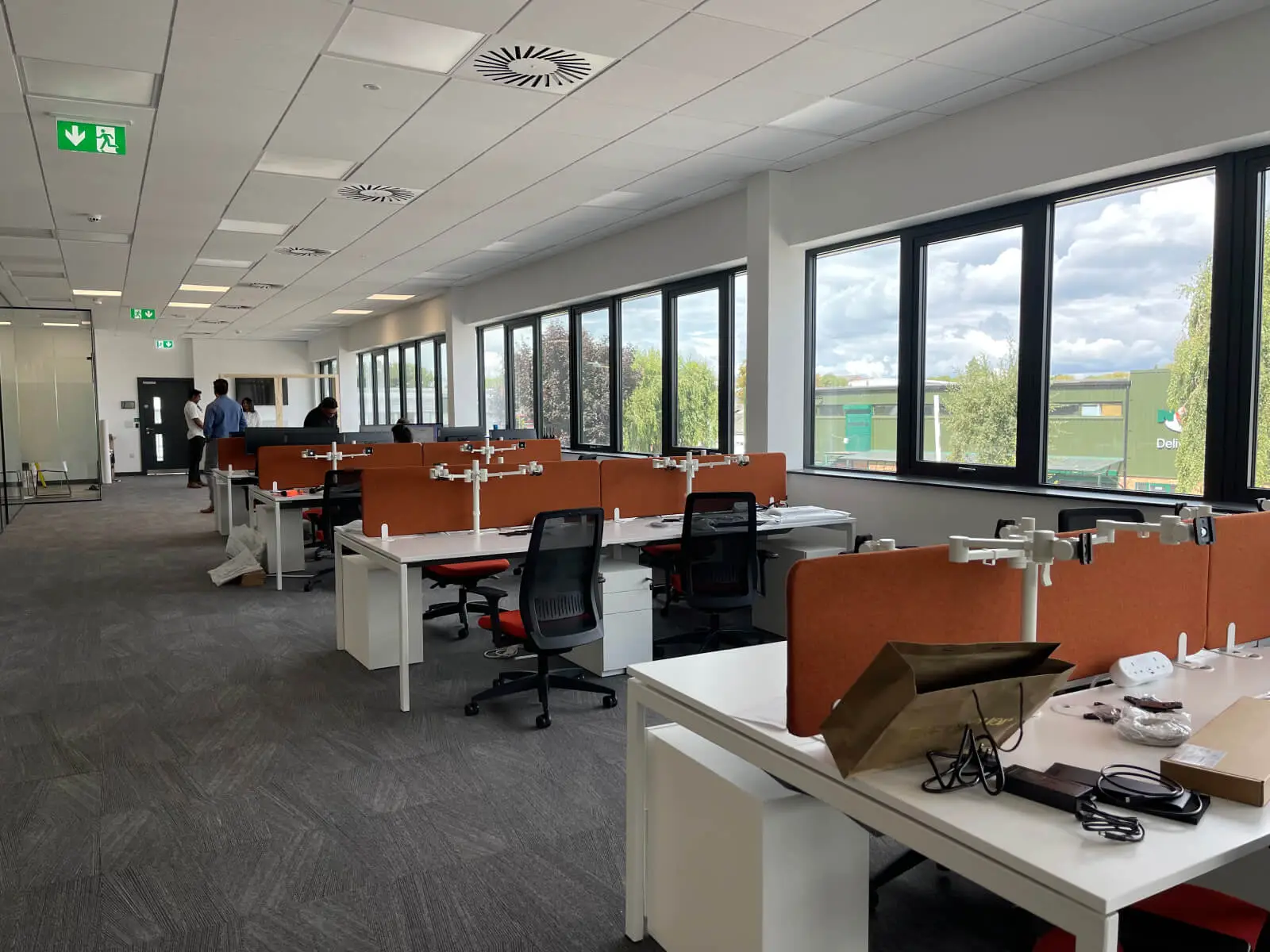 EFL office space with designer back to back desks, chairs, laminated wood flooring, suspended grid ceiling and glass partitions 19