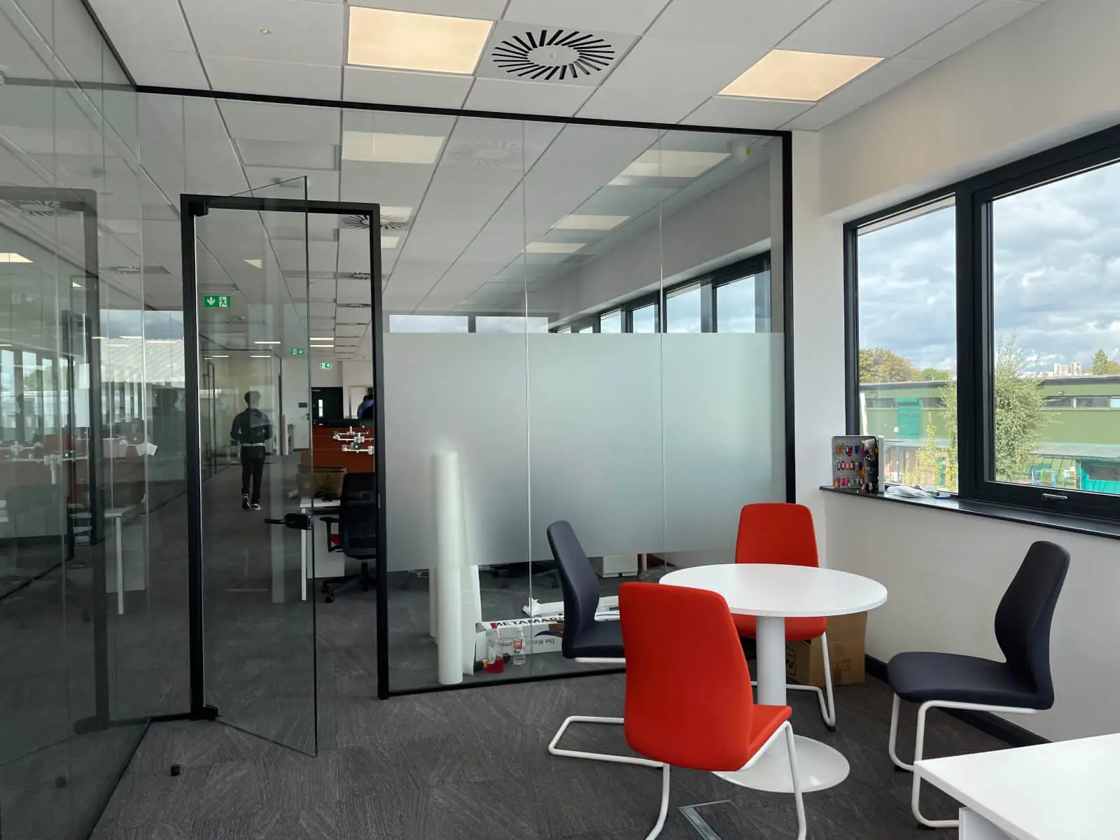 EFL office space with designer back to back desks, chairs, laminated wood flooring, suspended grid ceiling and glass partitions 24